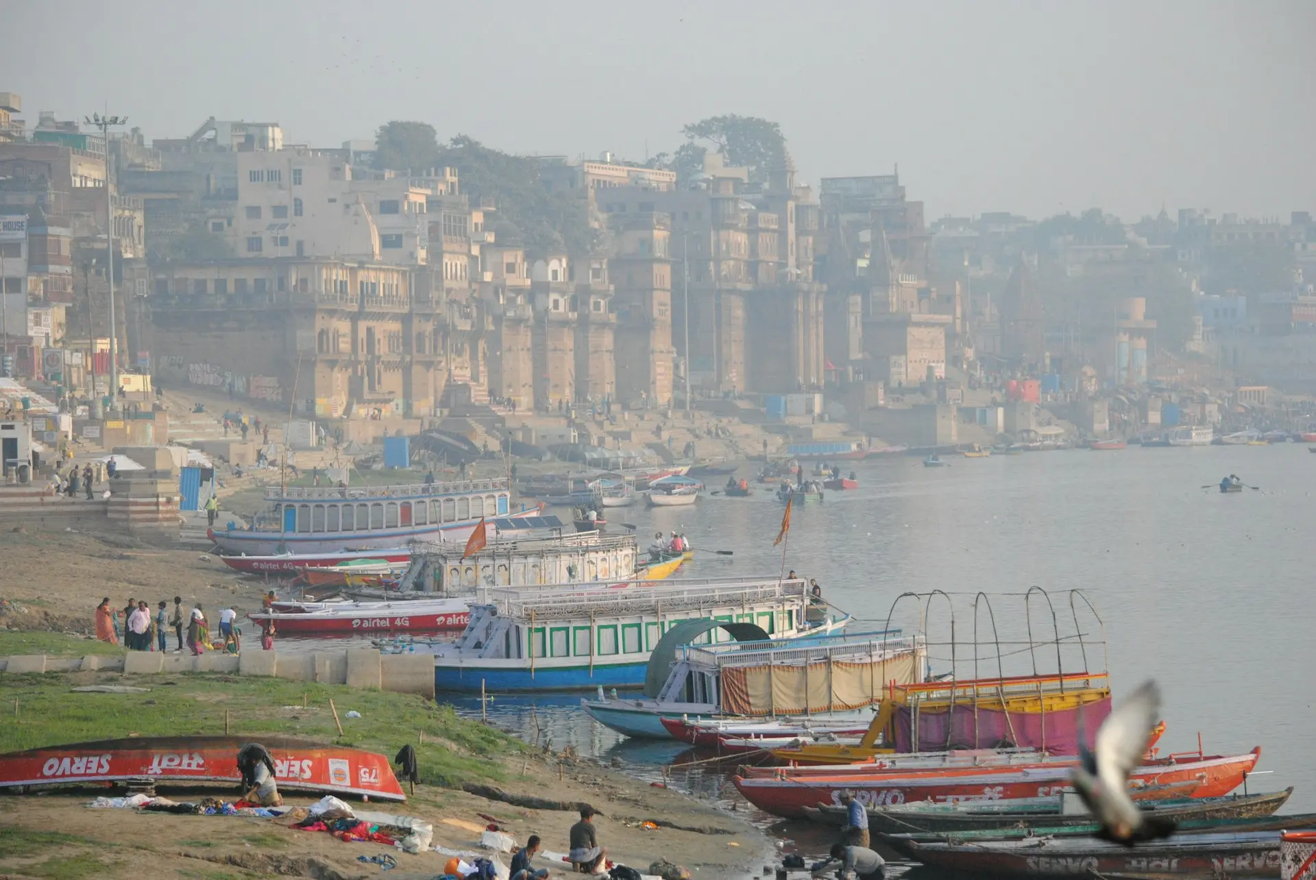 red and green boat on body of water near city buildings during daytime